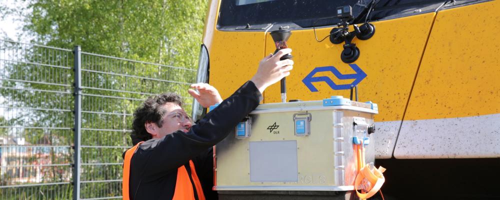 Bildtext: DLR-forskaren Paul Unterhuber kontrollerar det radiobaserade R2DATO-systemet på testbana i Amersfoort. Foto: DLR