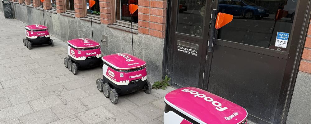 Ett nytt inslag i stadsbilden – uppskattat av många men också ifrågasatt. Foto: 	Moonhouse/Wikimedia Commons/https://commons.wikimedia.org/wiki/File:Foodora_delivery_bots_with_flags.jpg