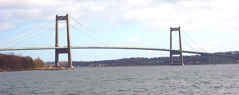 Det finns två broar i Danmark som heter Lilla Bältbron. Det är en äldre från 1935 och en nyare från 1970 (i bilden). Båda broarna går över Lilla Bält mellan Snoghøj (numera en del av Fredericias tätort) på Jylland och Middelfart på Fyn. Den nyare bron är en ren vägbro och vägen utgörs av en viktig motorväg. Foto: Wikipedia Commons. Kredit: Kredit:  Ävar Arnfjöro Bjarmason.