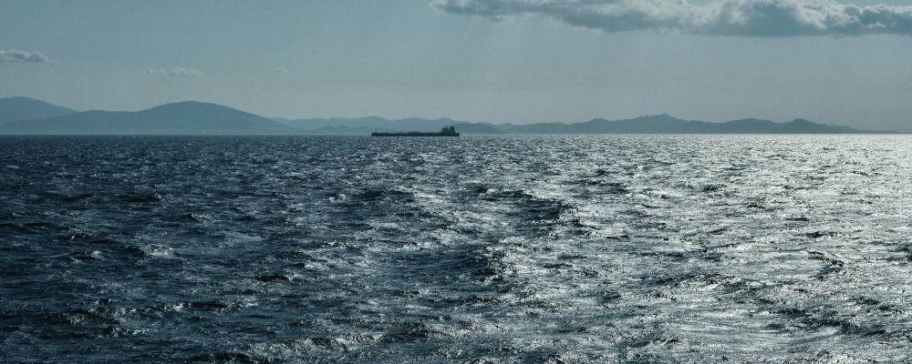 Genrebild på öppet hav med fartyg i fjärran. Foto: Giandomenico Pozzi/Unsplash