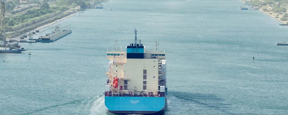 Ett stort containerfartyg med Maersks färger vid ingången till Suezkanalen, vars stränder omges här av grön vegetation. Foto: Maersk