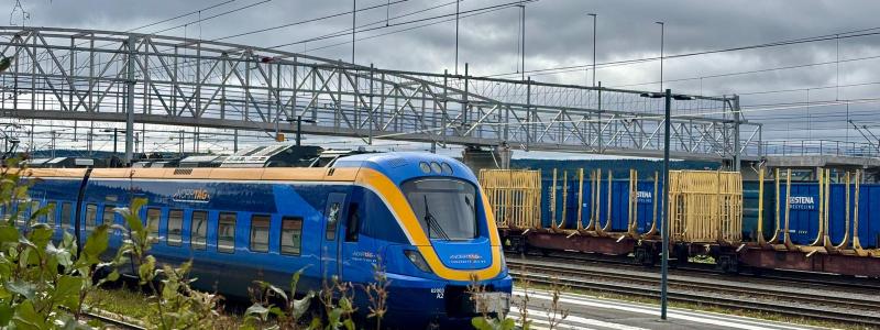 Ett persontåg från Norrtåg passerar bangården i Östersund, med godsvagnar i bakgrunden. Foto: Stina Wickenberg