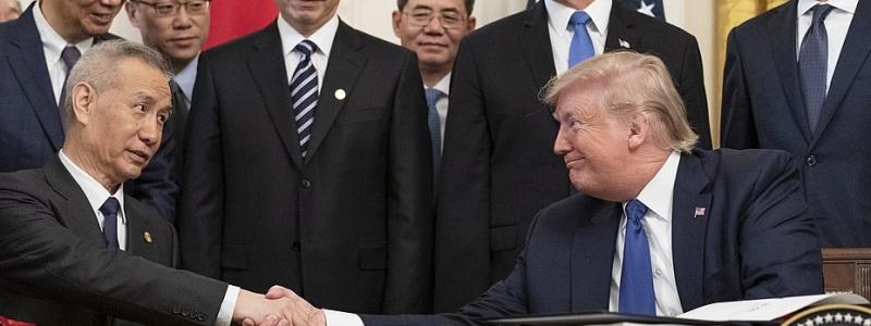 Undertecknande av fas ett i handelsavtalet mellan USA och Kina den 15 januari 2020. USA:s dåvarande president Donald J. Trump och Kinas vice premiärminister Liu He undertecknade fas ett av handelsavtalet mellan USA och Kina i Vita husets östra rum.(Officiellt foto från Vita huset, Shealah Craighead) Wikipedia Common Lic.