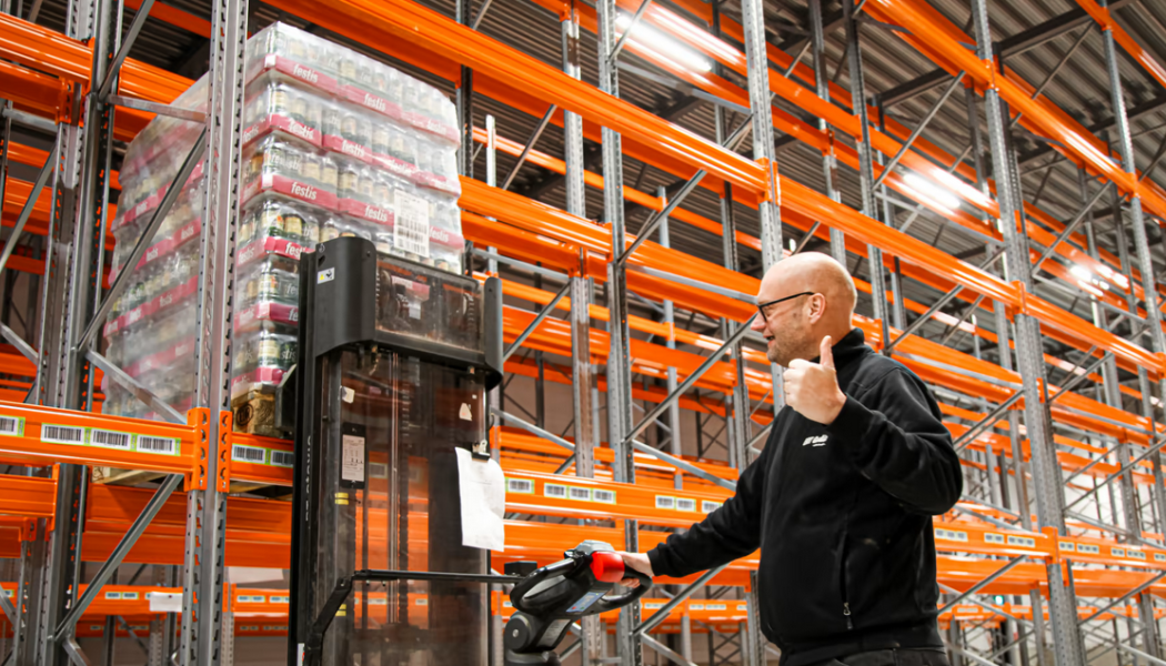 Vd Nichlas Ernstsson lyfter in första pallen i ERT Godis nya lagerlokal. Foto: ERT Godis