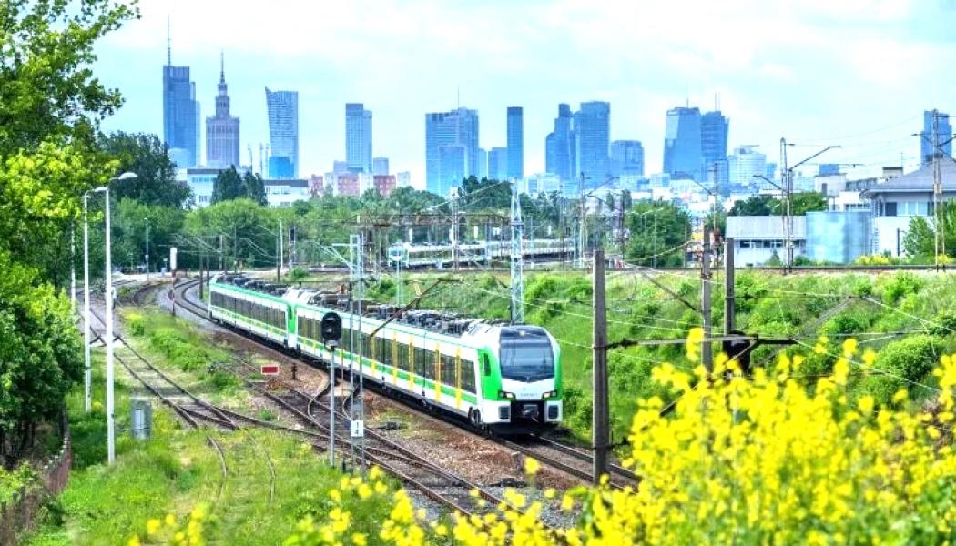 FLIRT-tåg från Stadler på väg i Warszawas omgivningar. I bakgrunden syns den polska huvudstaden skyline. Foto: Stadler