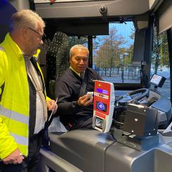 Förarcoach Åke Håkansson ger bussföraren René Alvarez en tablettask i kampanjen ”Bälte på, mobilen av”. Foto: Bergkvarabuss