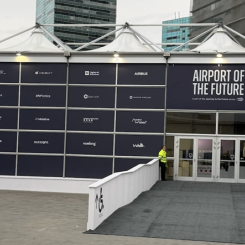 Entrén till Airport of the Future-zonen vid södra ingången till Fira de Barcelona. På fasaden syns samtliga partners – från Airbus och AENA till Outsight, NTT Data och Vueling. Zonen är en del av MWC:s "Journey to the Future"-serie, med flyg som första bransch. Foto: Nicholas Christiansen.