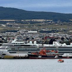 Viking Polaris ligger i hamnen i Chile för reparation efter att ha drabbats av en jättevåg ungefär tio dagar tidigare. Bilden togs den 12 december 2022 i Punta Arenas, som ligger i bakgrunden. Ett DAP-fartyg, liksom en tenderbåt från kryssningsfartyget Viking Jupiter, är i förgrunden. Foto: Wikipedia Common, Kredit: Nolabob